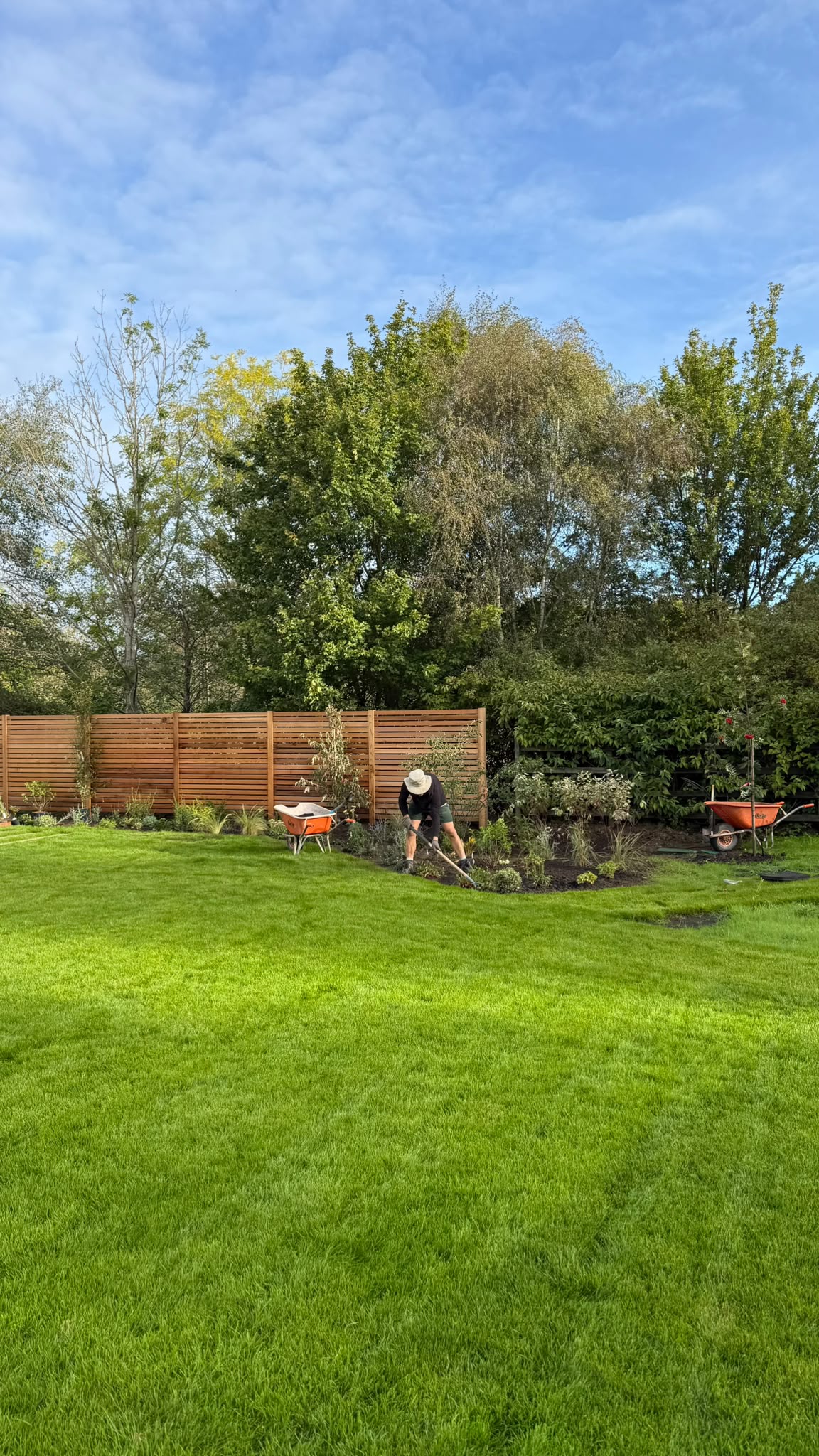 Team working planting borders along fencing on a maintained garden