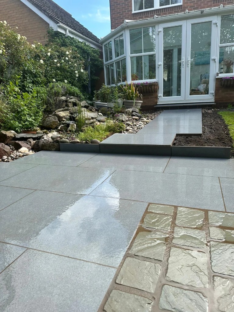 Porcelain patio path leading to conservatory with rockery water feature