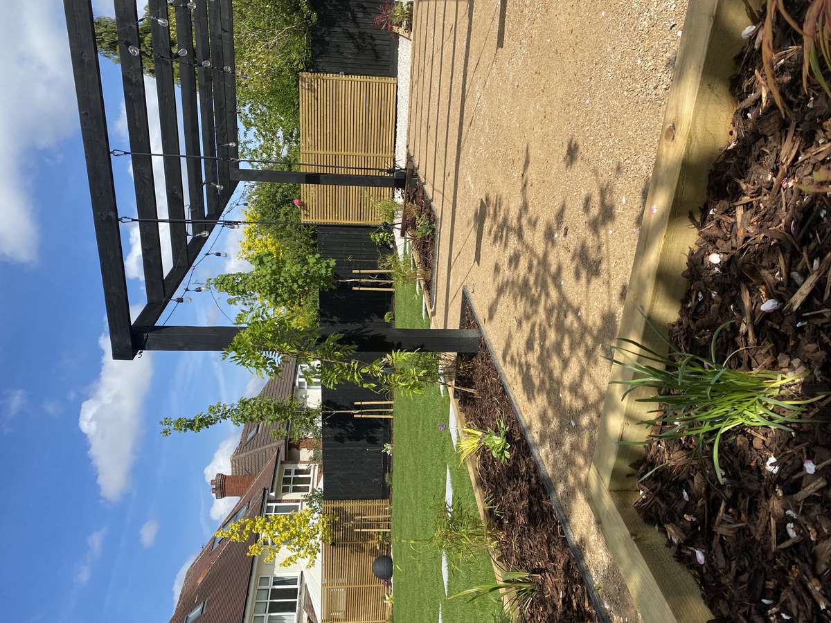 Full garden redesign in Oadby, Leicestershire featuring a porcelain patio, large pergola, fire pit area and timber seating