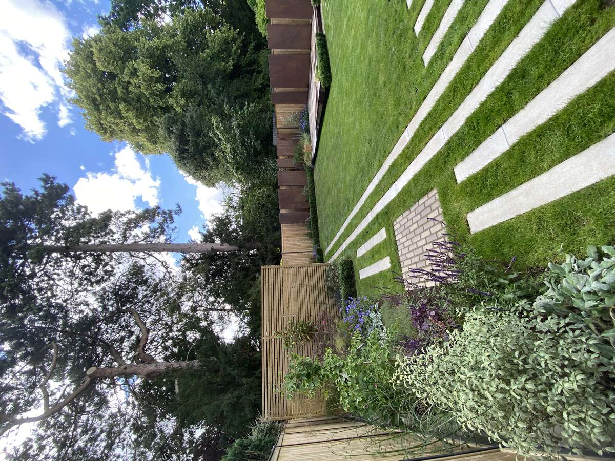 Modern garden redesign in Clarendon Park, Leicestershire with outdoor kitchen, Balau decking, water feature and porcelain patio