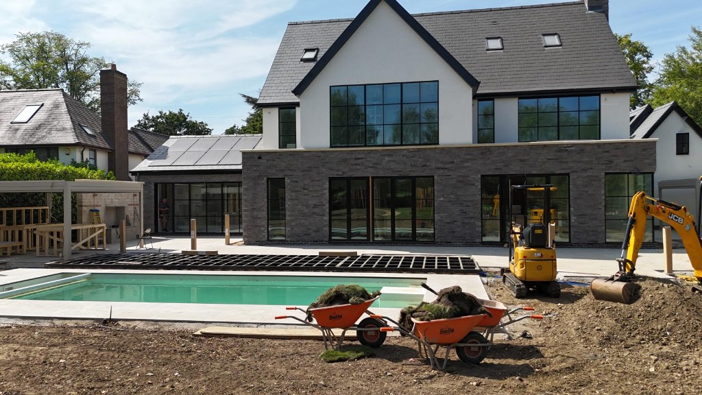 Swithland luxury pool garden under construction - full rear of the house with pool terrace, decking frame and plant on site