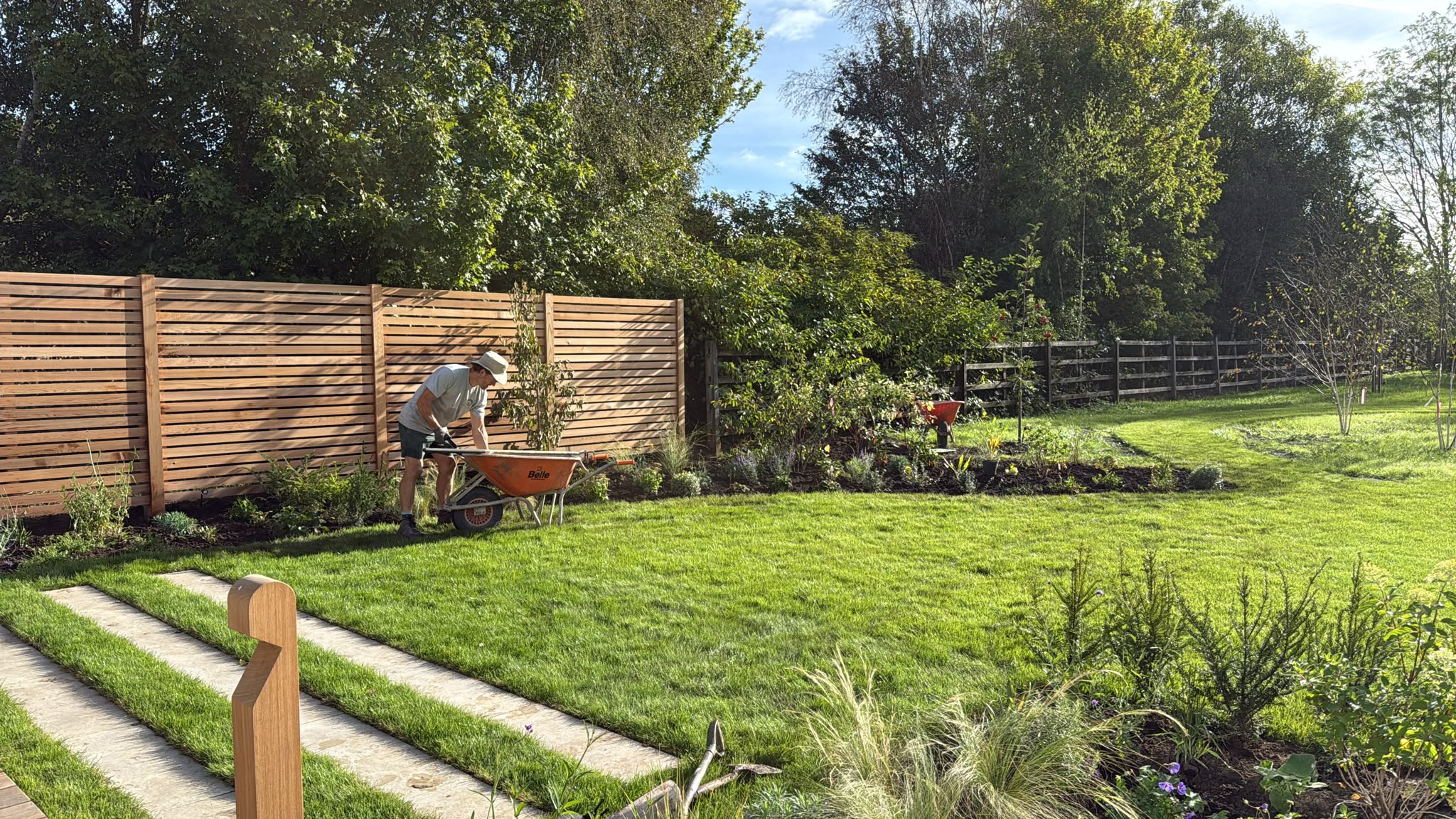 Team finishing planting along the fence with striped lawn
