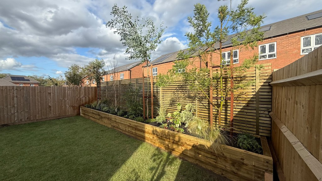 Finished new-build garden at Broadnook Village, Rothley, with lawn, raised timber planter, slatted fence and mature trees